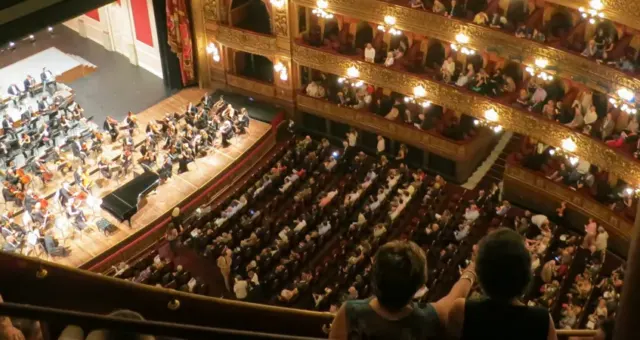 Orchestra hall with balconies filled with audience