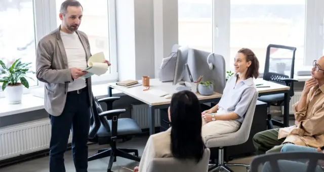 Team gathered in a bright office listening to a colleague