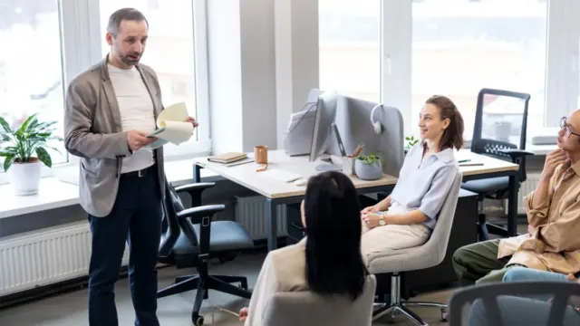 Team gathered in a bright office listening to a colleague