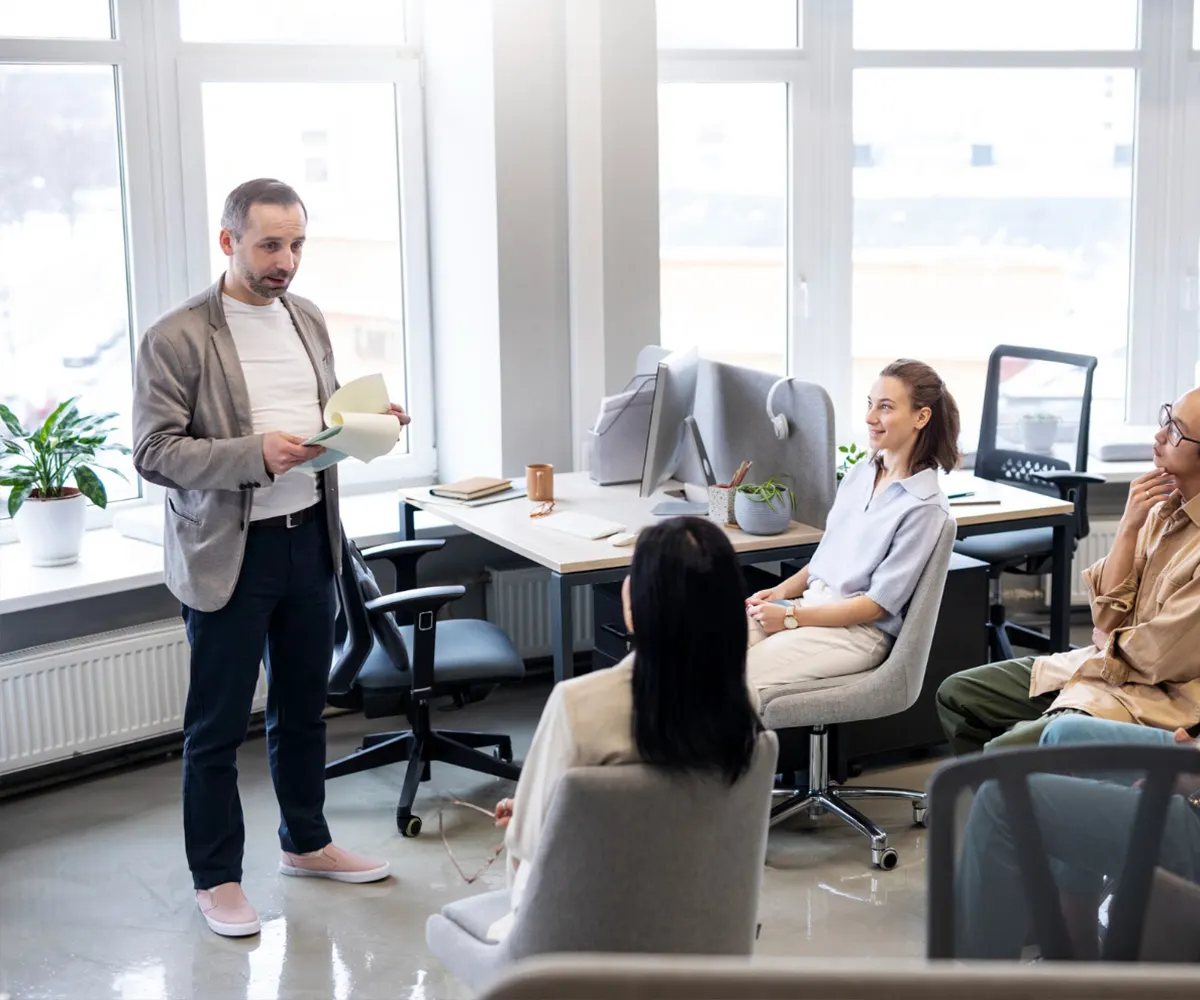 Team gathered in a bright office listening to a colleague